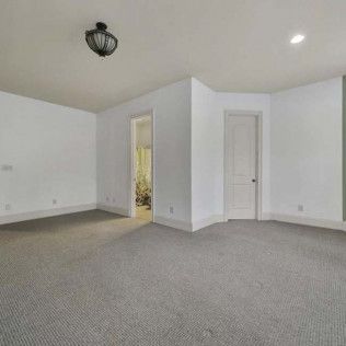 Empty room with gray carpet, white walls, two doorways, and a ceiling light.