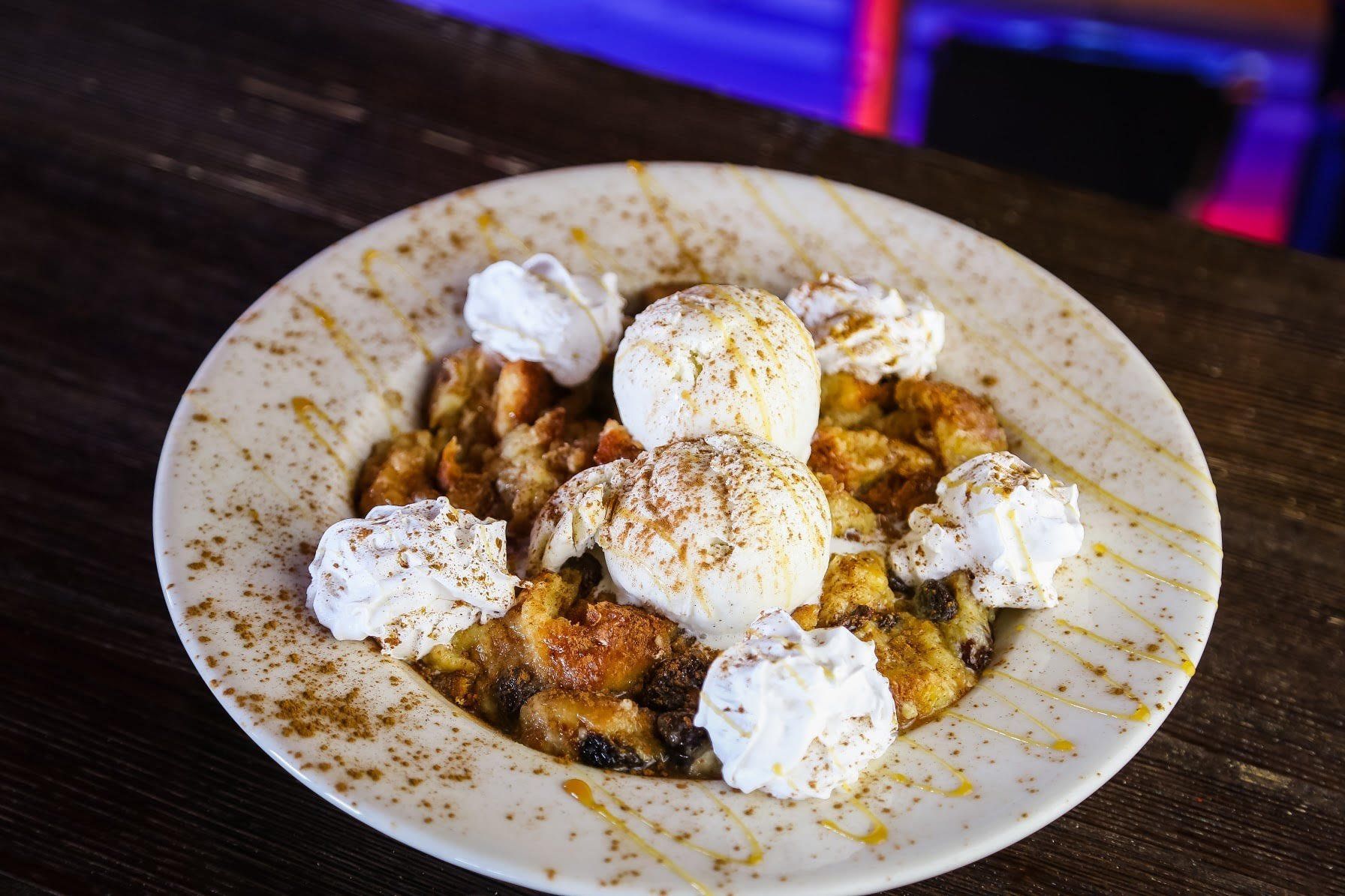 Dessert plate with whipped cream dollops and powdered sugar on a wooden table