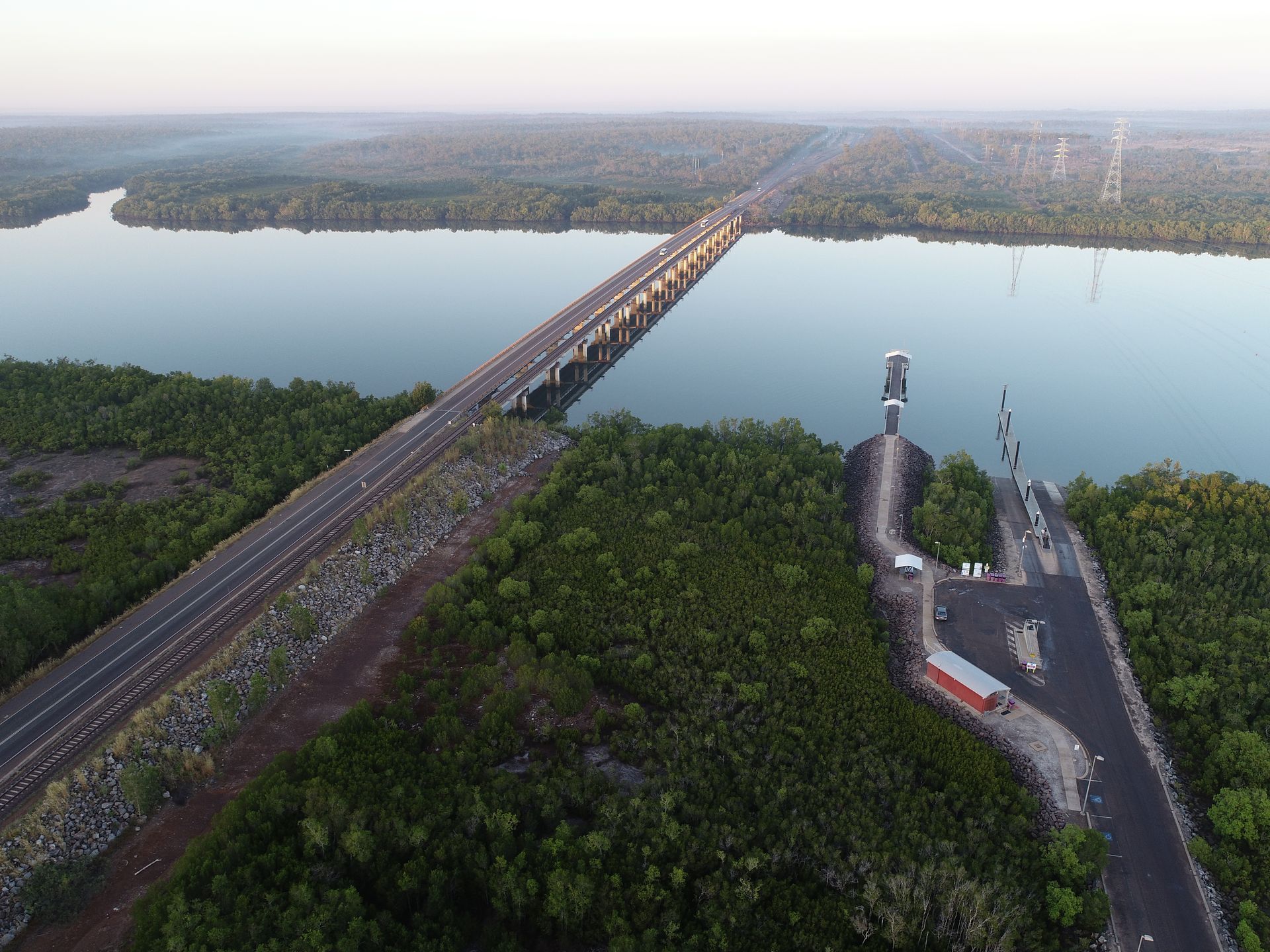 An aerial view of a bridge over a river in the Top End surrounded by trees