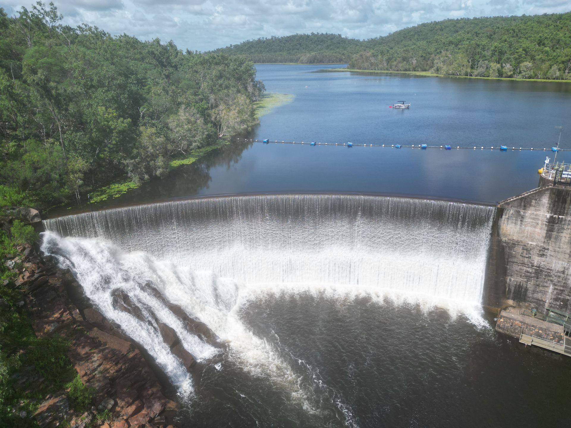 Rise boat on water reservoir near a spilling dam, while they do a bathymetric survey. 