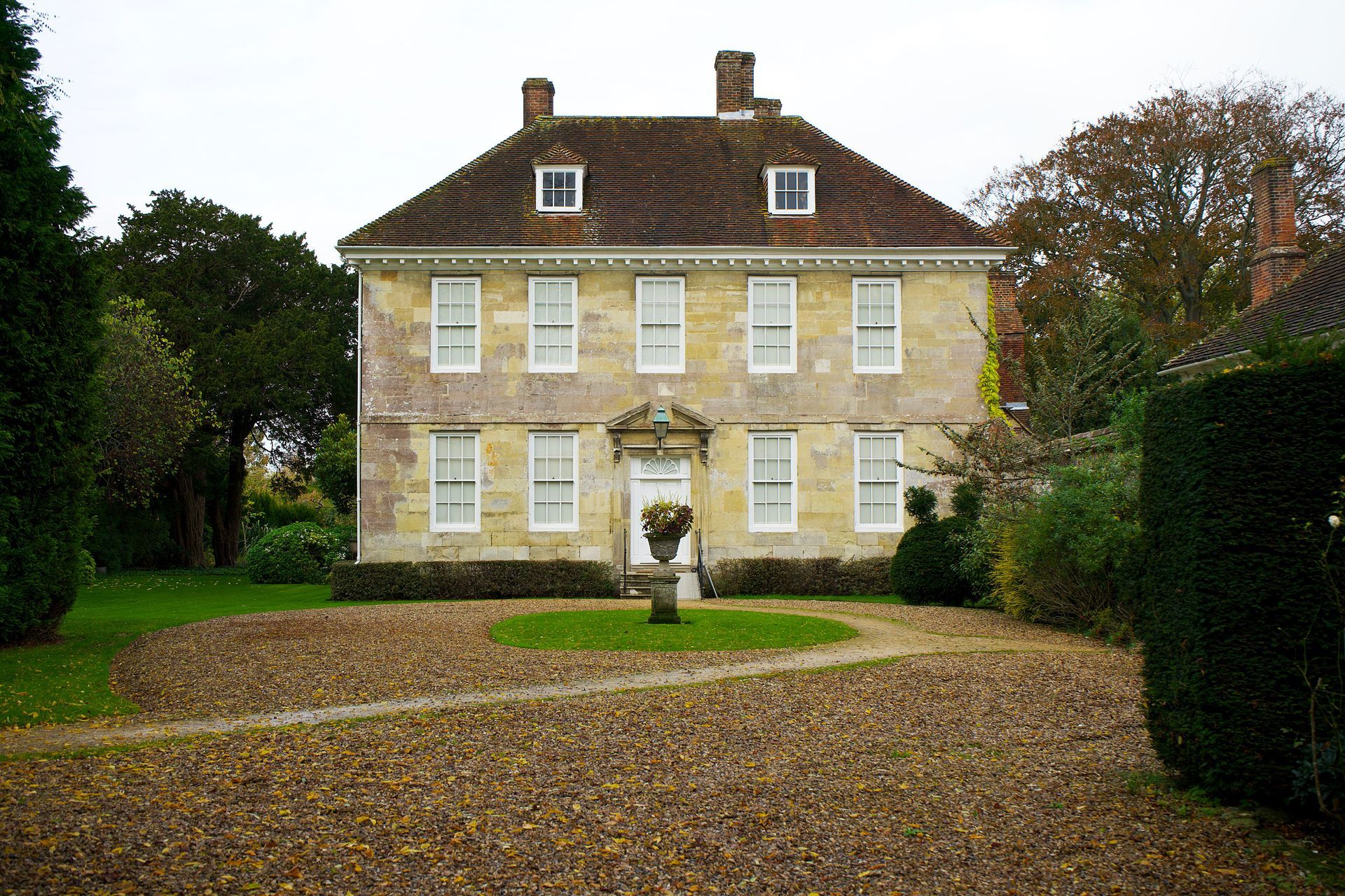 Gravel driveway leading through a planted garden to a traditional house