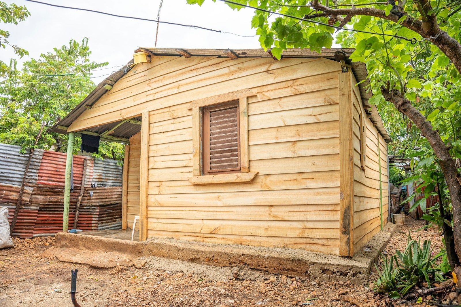 Timber garden shed on a raised concrete base with exposed ground around it