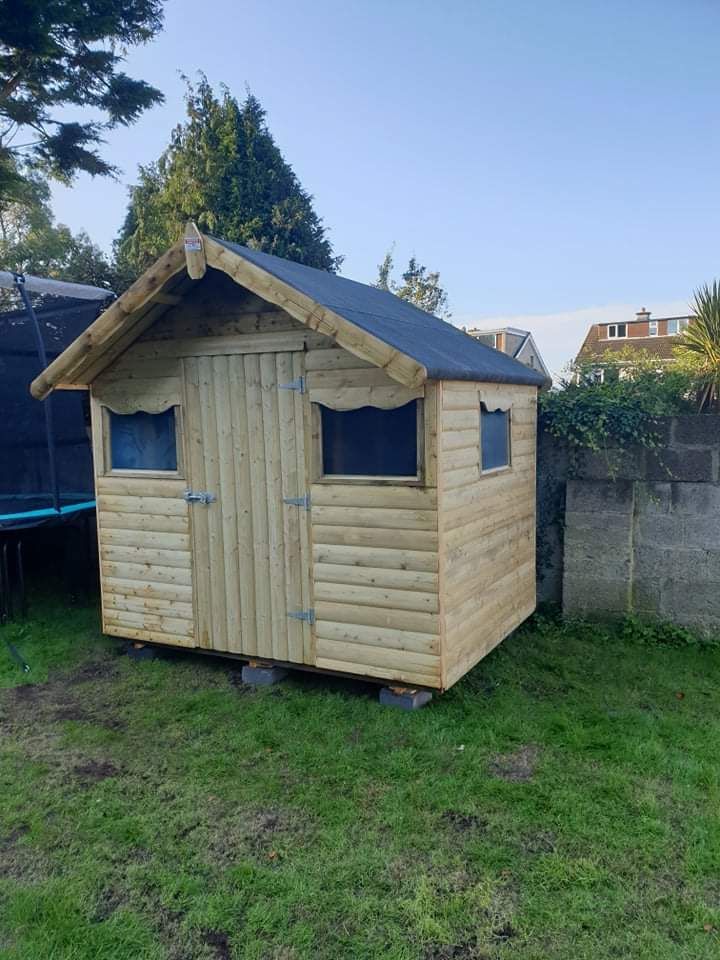 Wooden shed with a black roof, two windows, and a door, in a grassy backyard.