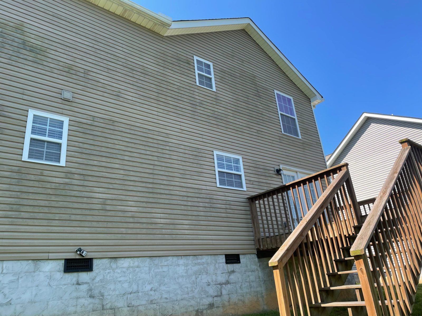 A house with a wooden deck and stairs leading up to it.