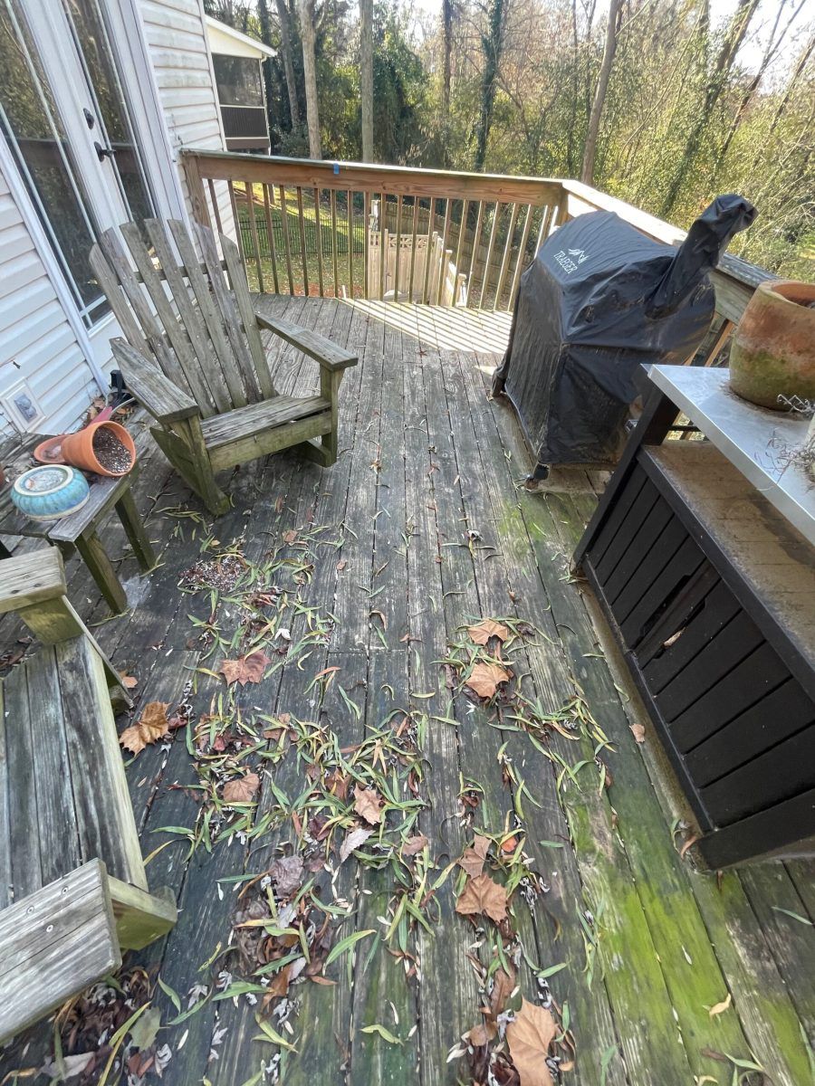 A wooden deck with chairs and a grill on it.