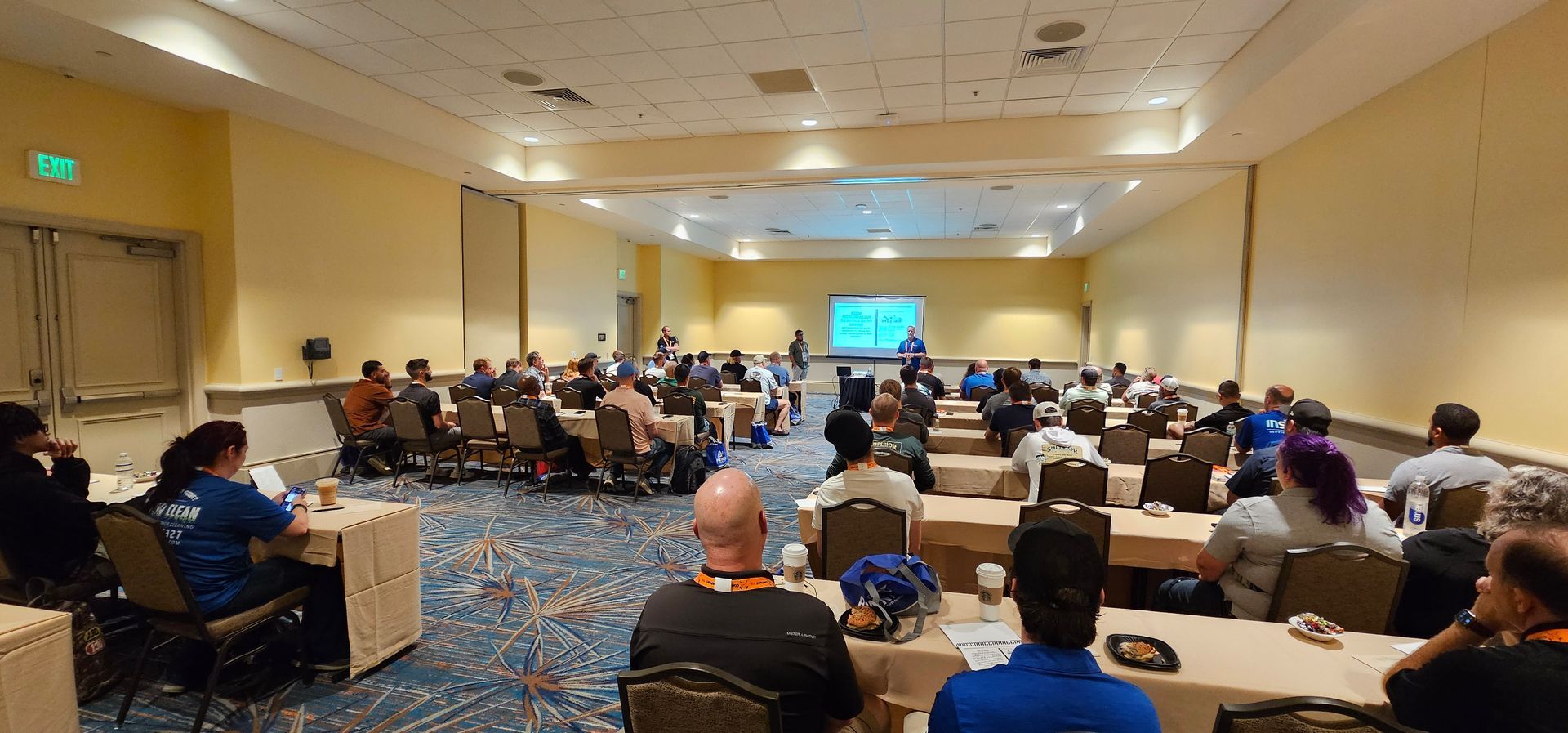 Conference room with attendees seated in rows facing a presentation screen at the front