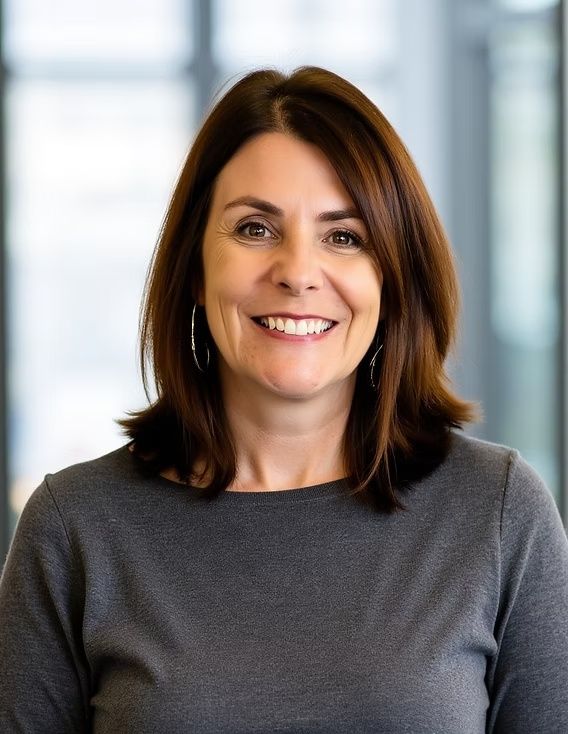 Smiling person in a gray sweater in a softly lit office setting