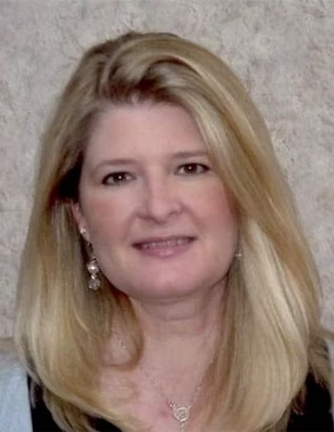 Portrait of a smiling woman with long blonde hair against a neutral background