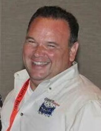Smiling man in a white shirt with a red lanyard against a neutral background