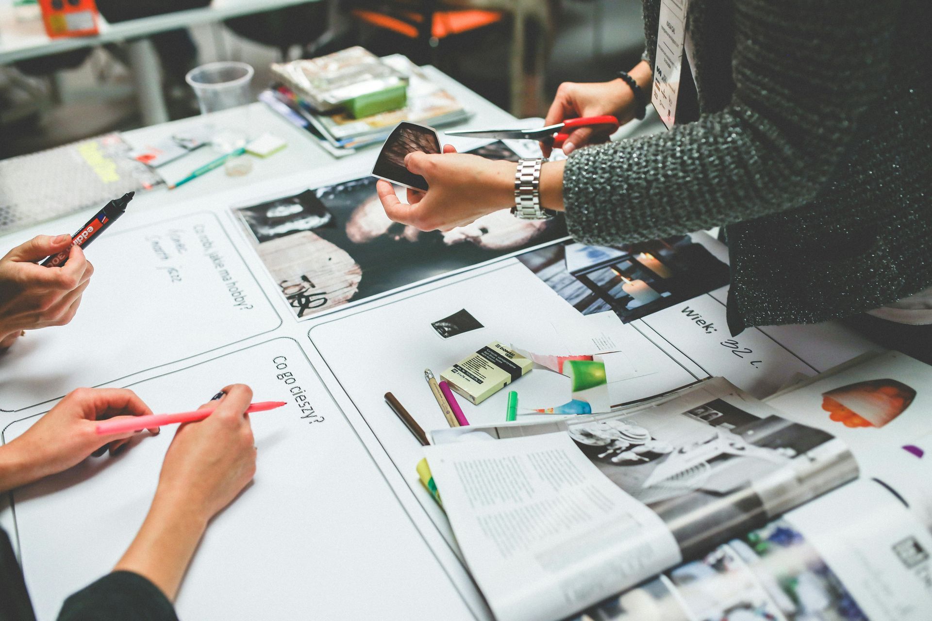 People reviewing colorful design layouts and notes on a table, with hands pointing and writing.