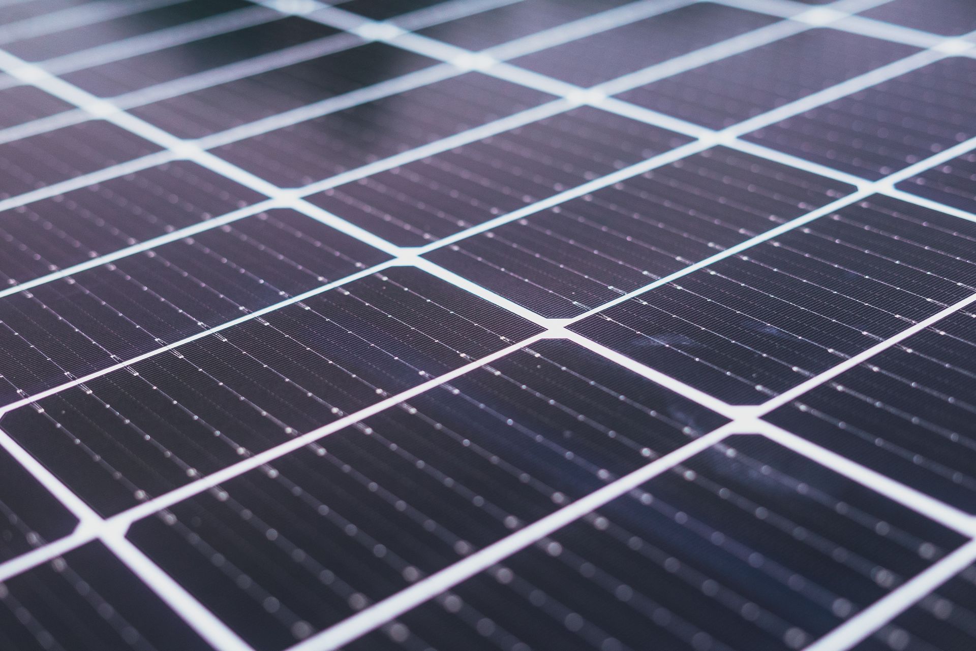 Close-up of dark solar panels in a grid, reflecting light at an angle
