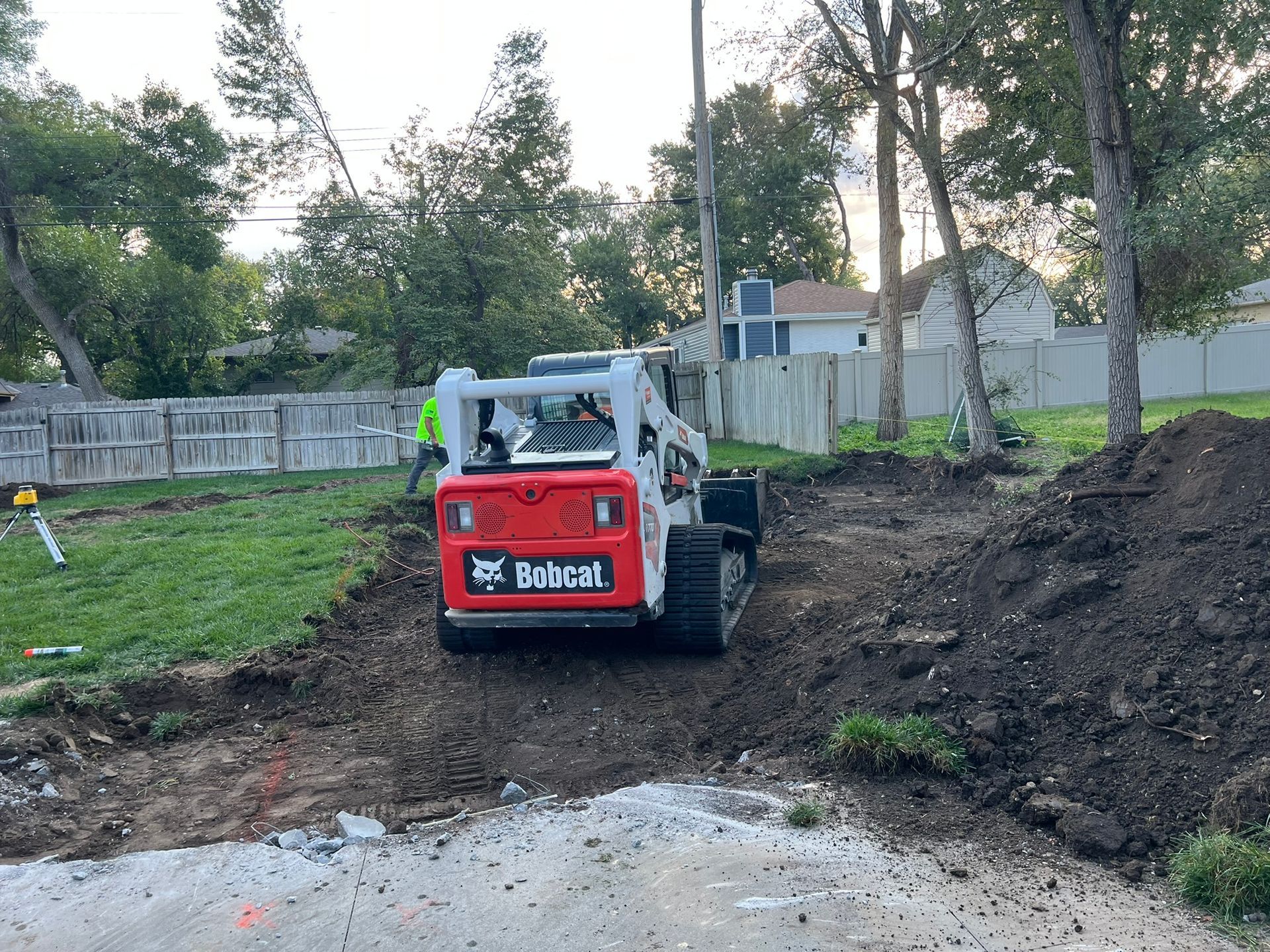 Excavator demolishing a brick building, creating dust; outdoors.