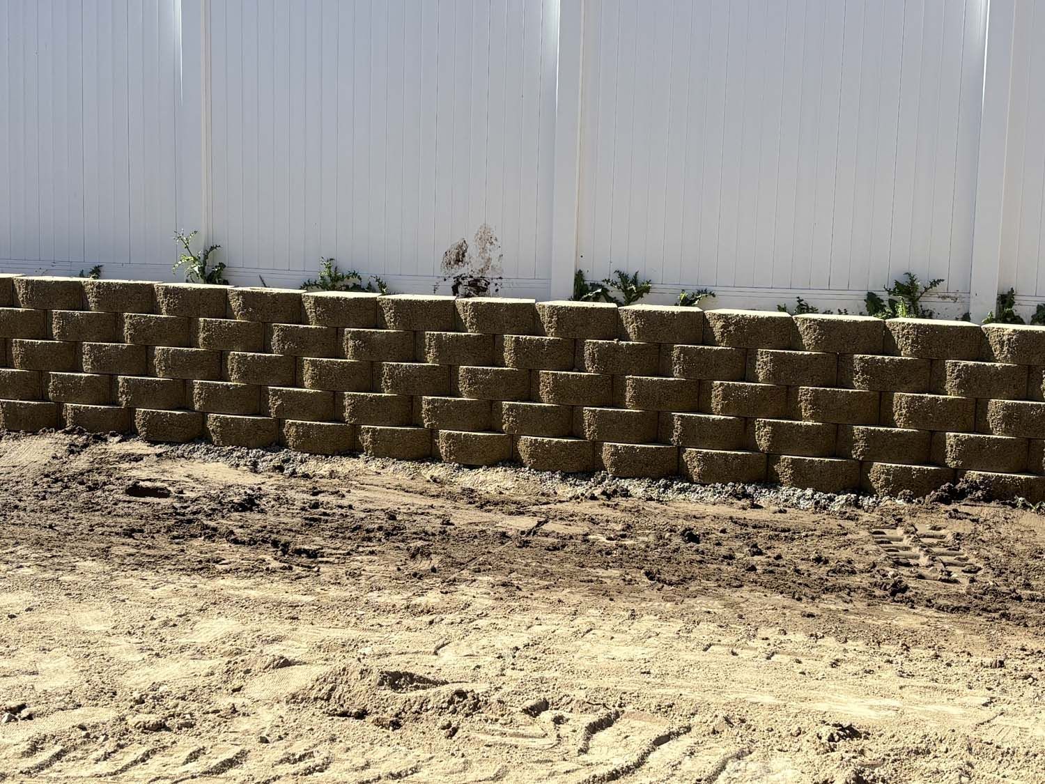 A brick wall with a white fence in the background