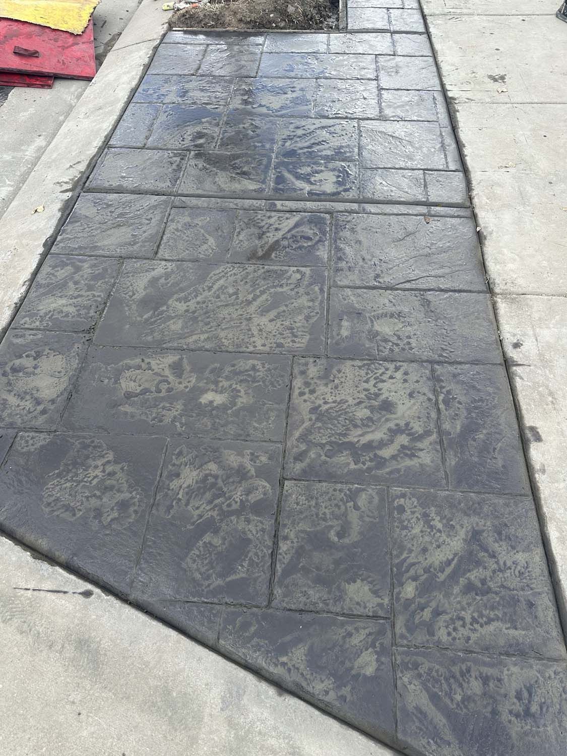 A concrete walkway with a brick pattern is being built.