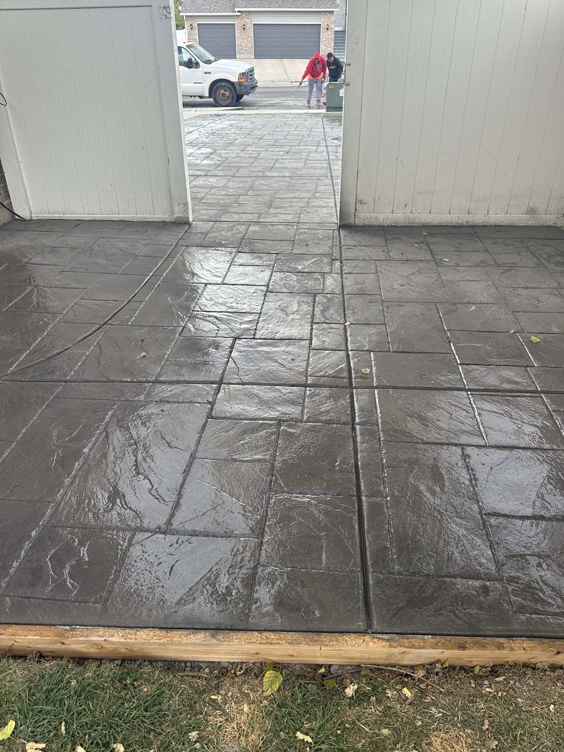 A concrete driveway with a white truck parked in the background.