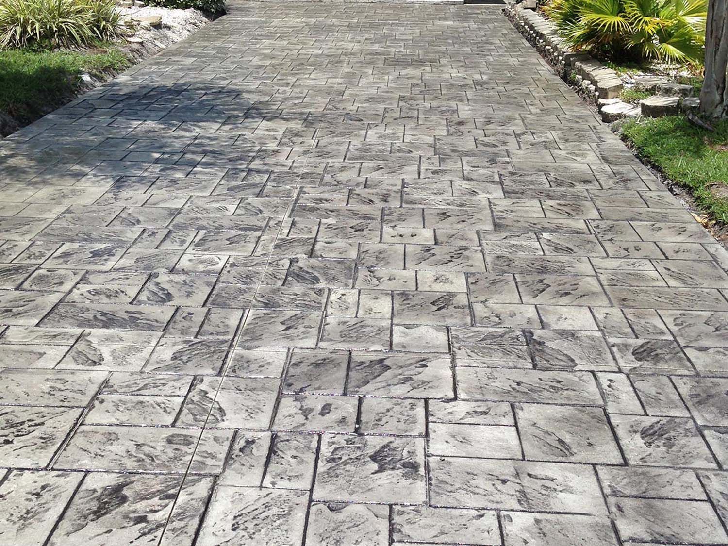 A gray brick driveway leading to a house.