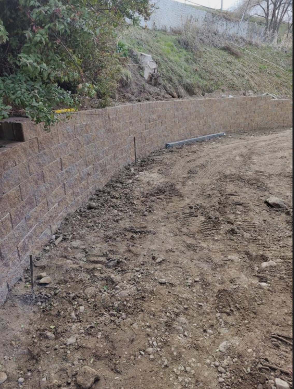 A brick wall is being built on top of a dirt field.