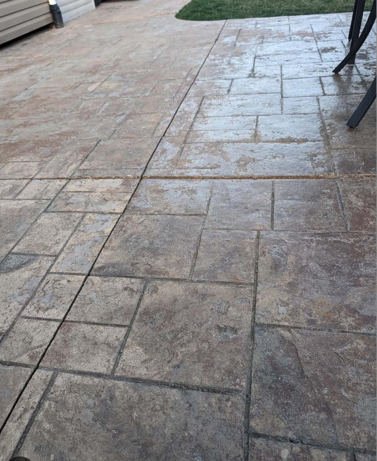 A patio with a concrete walkway and a table and chairs.