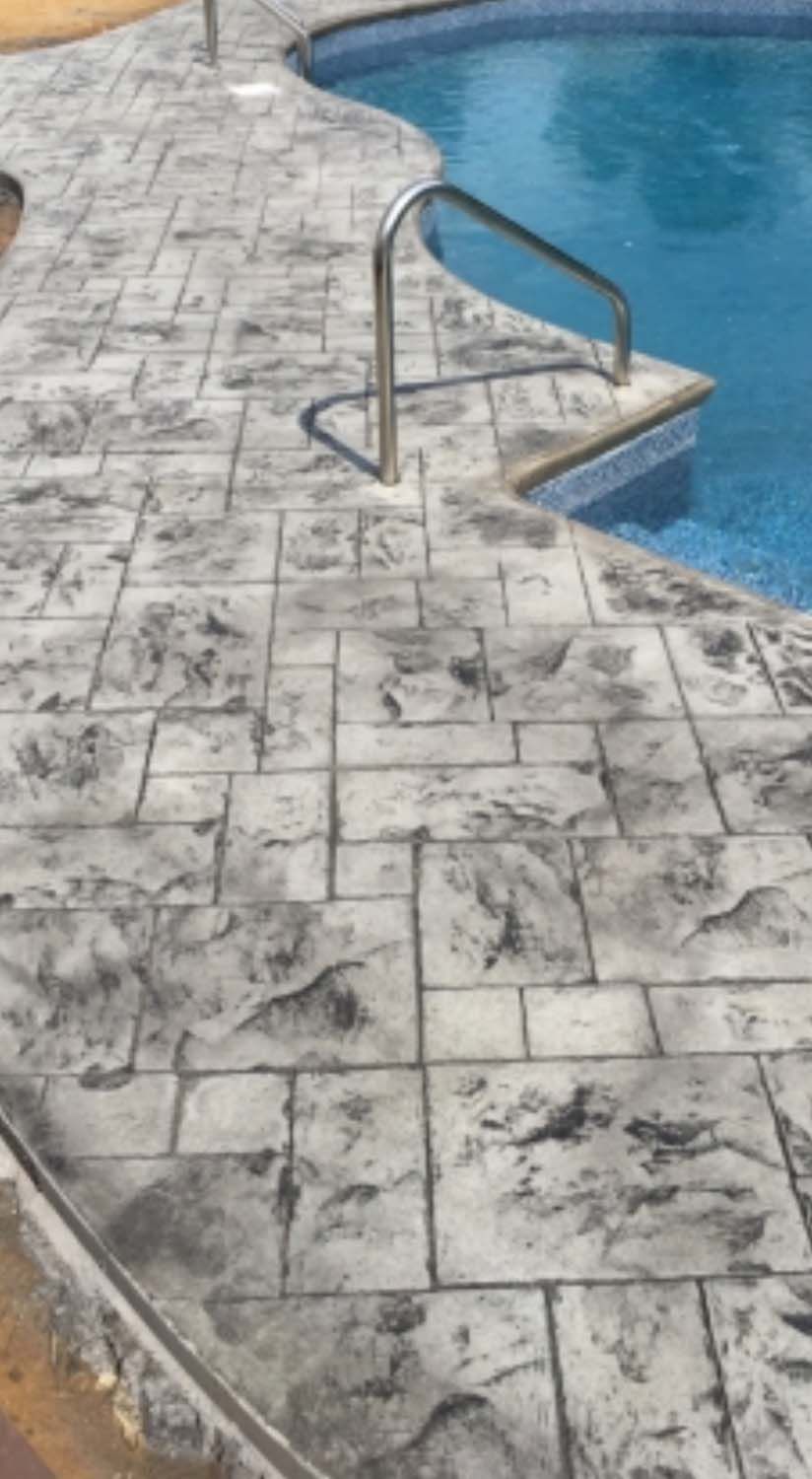 A concrete walkway leading to a swimming pool.