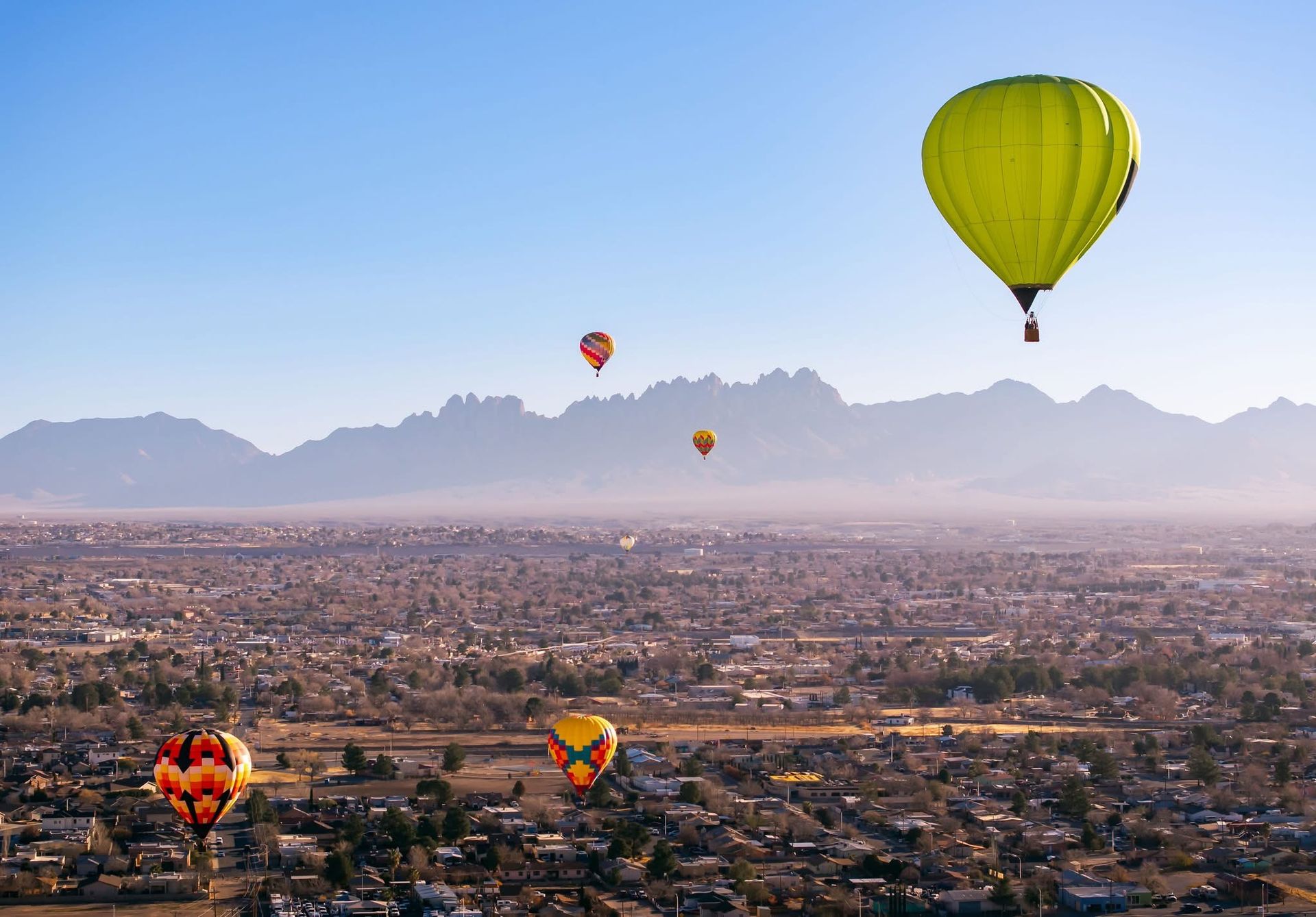 A group of hot air balloons are flying over a city.