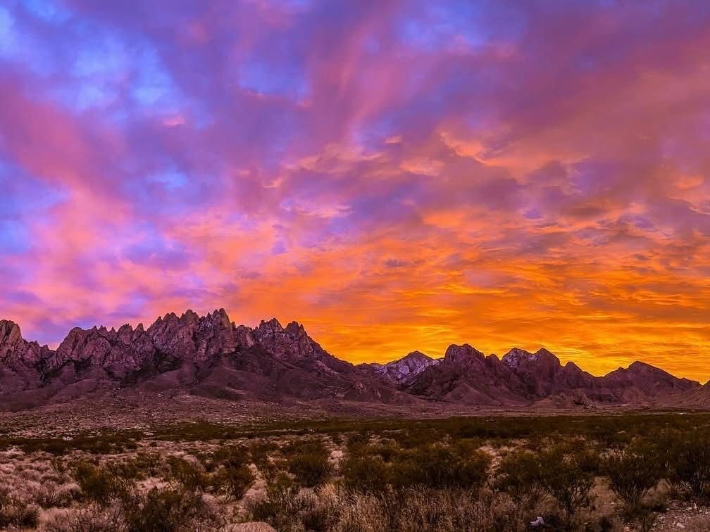A sunset in the desert with mountains in the background