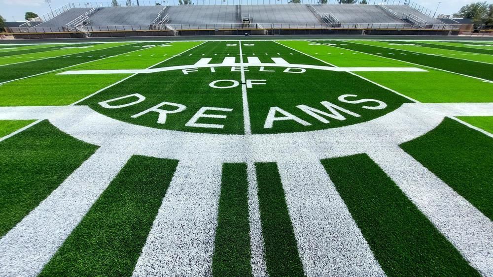 A soccer ball is sitting on the grass in front of a stadium.