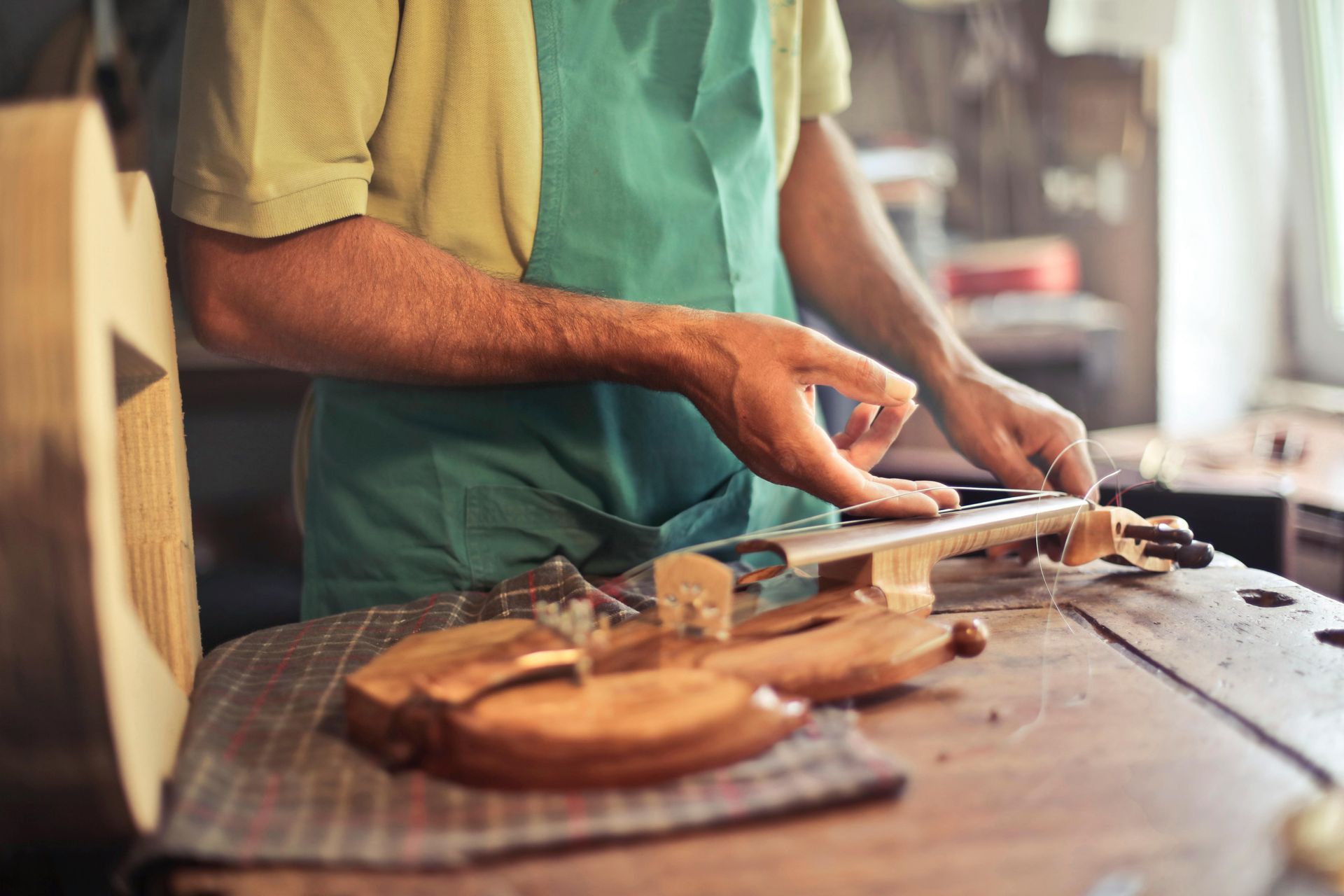 A man is working on a violin in a workshop.
