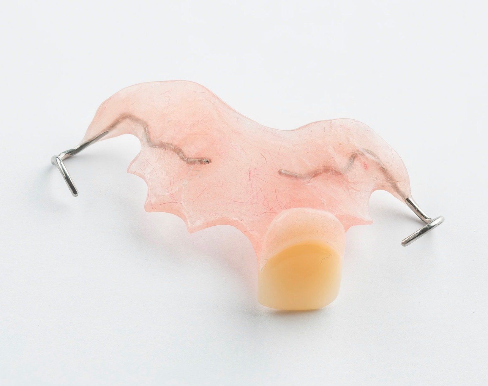 Pink translucent umbrella-shaped object with metal pins and a yellow base on a white background