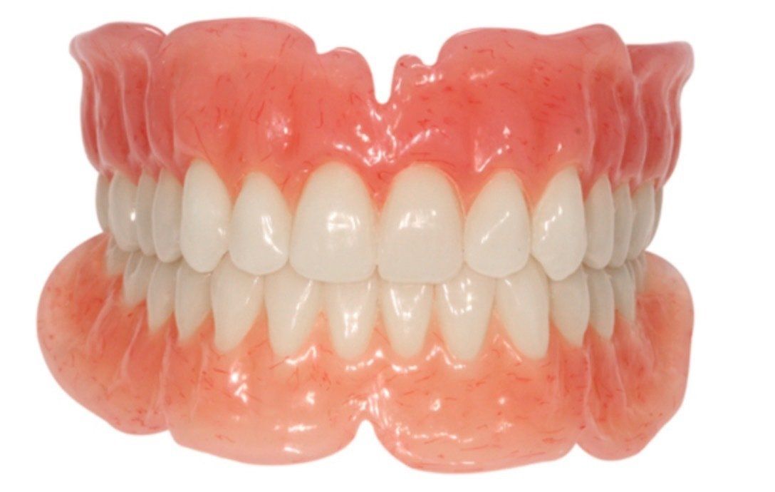 A set of realistic pink and white dentures on a plain white background