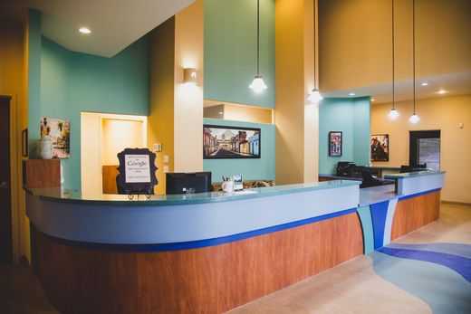 Empty hotel reception desk with teal walls, wood paneling, and blue counters.