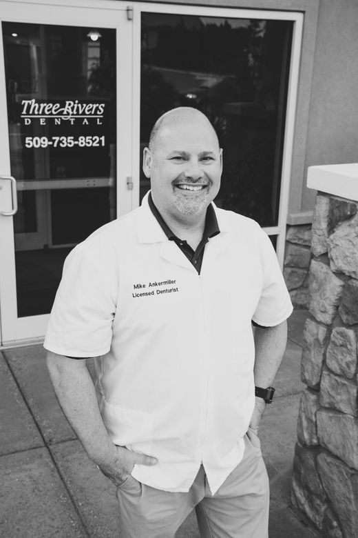 Smiling man in white polo standing outside Three Rivers building entrance