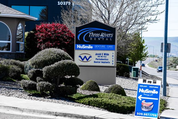 Nisqually Health Center sign beside trimmed shrubs on a sunny roadside