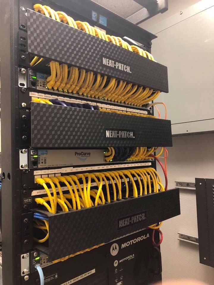 Server rack with multiple black network switches and many yellow cables in a data center