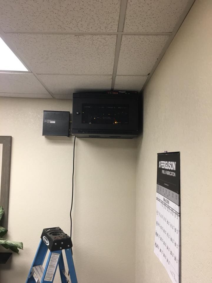 Ceiling-mounted black projector and speaker above a blue ladder in an office hallway