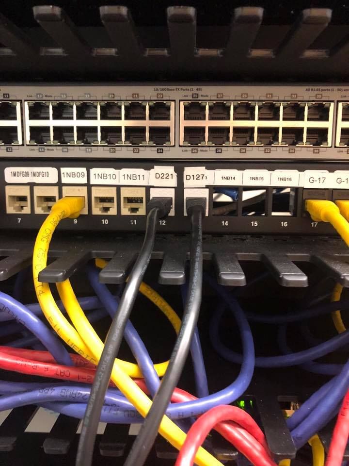 Close-up of a network switch with rows of ports and yellow, blue, and black ethernet cables plugged in