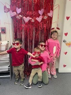 A group of children wearing heart shaped sunglasses are posing for a picture.