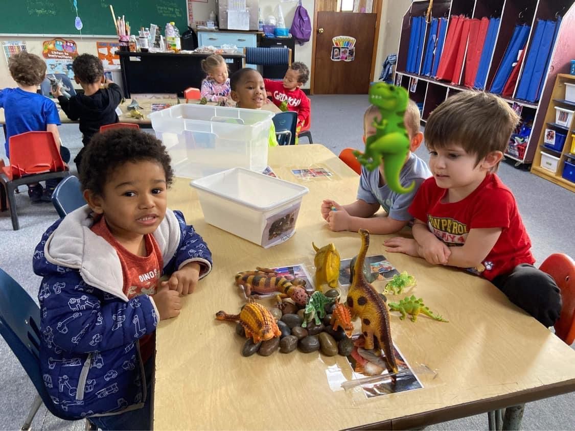 A group of children are sitting at a table painting easter eggs.