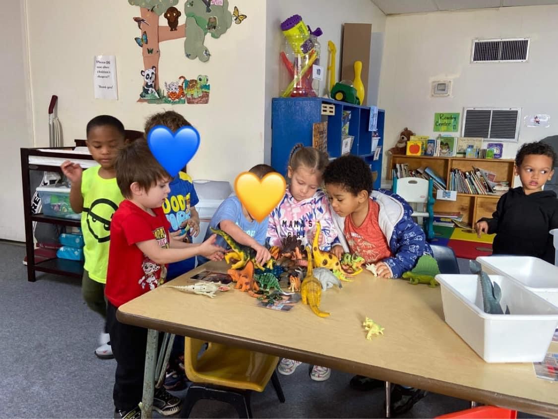 A group of children are playing with toys at a table in a classroom.