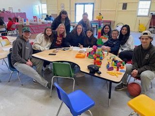 A group of people are sitting around a table with toys on it.