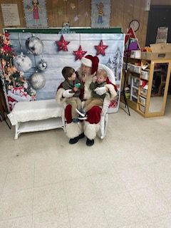 Santa claus is sitting in a chair with two children.