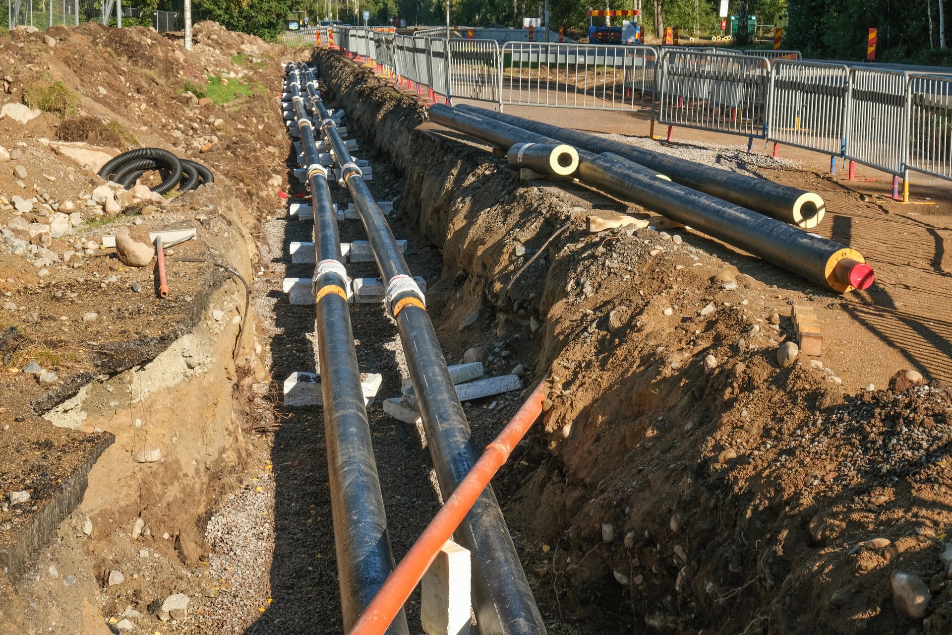 A bunch of pipes are laying in the dirt