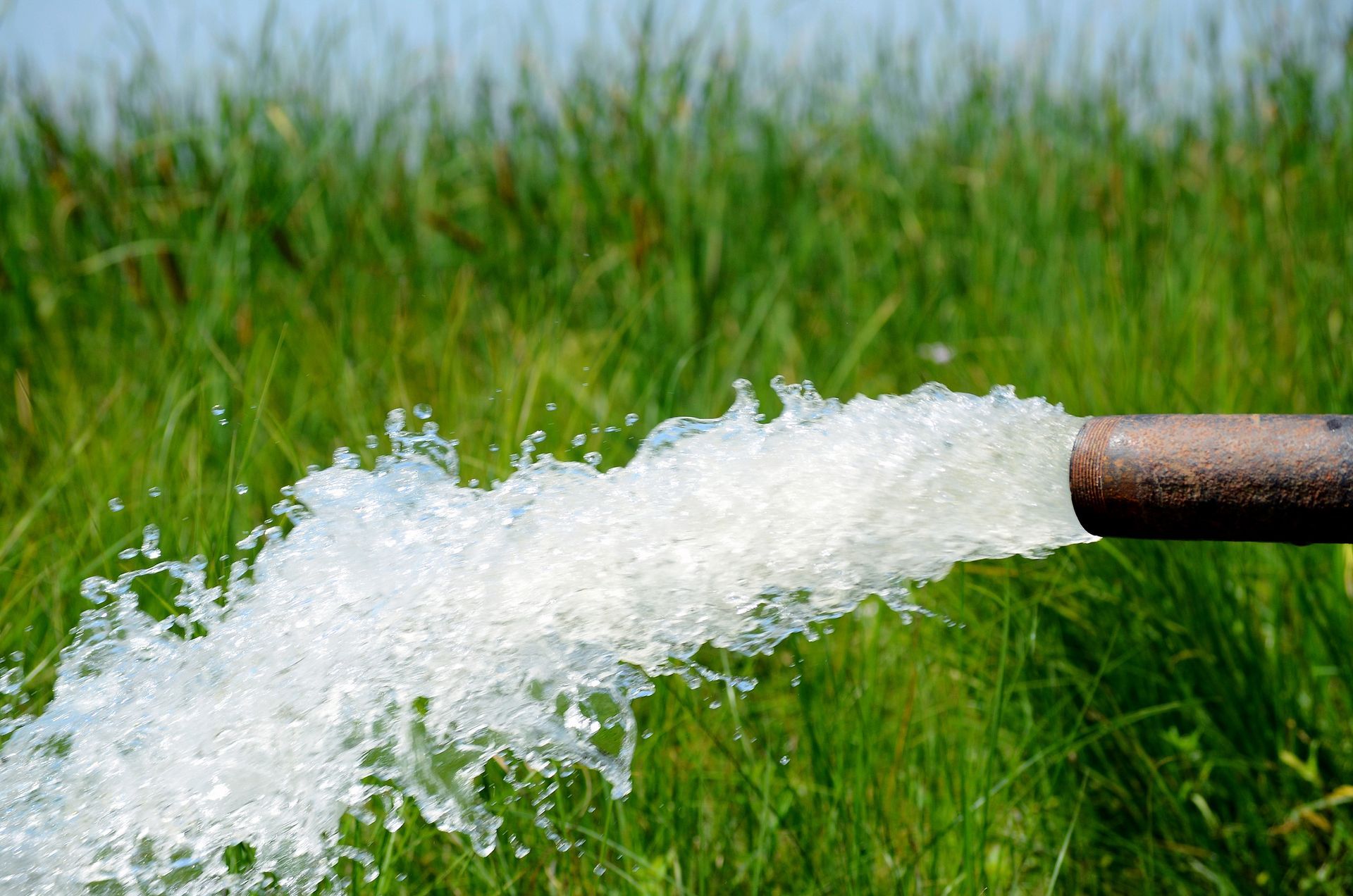 Water is coming out of a pipe in a field. Water is coming out of a pipe in a field.