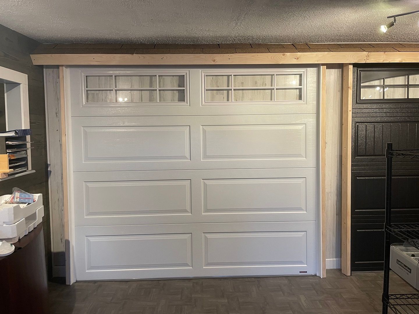 White garage door with small upper windows in a dimly lit interior space.