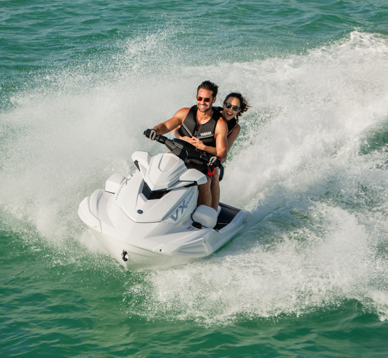 A man and a woman are riding a jet ski in the ocean.