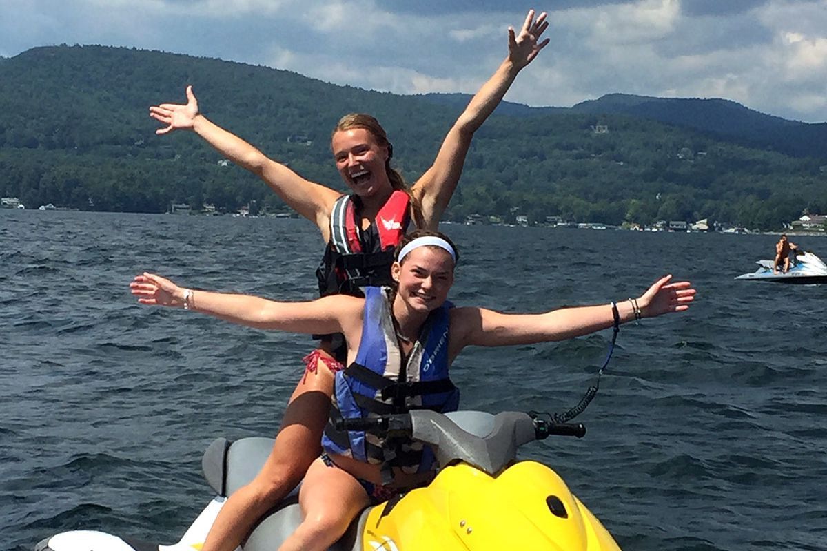 Two women are riding a jet ski on a lake.