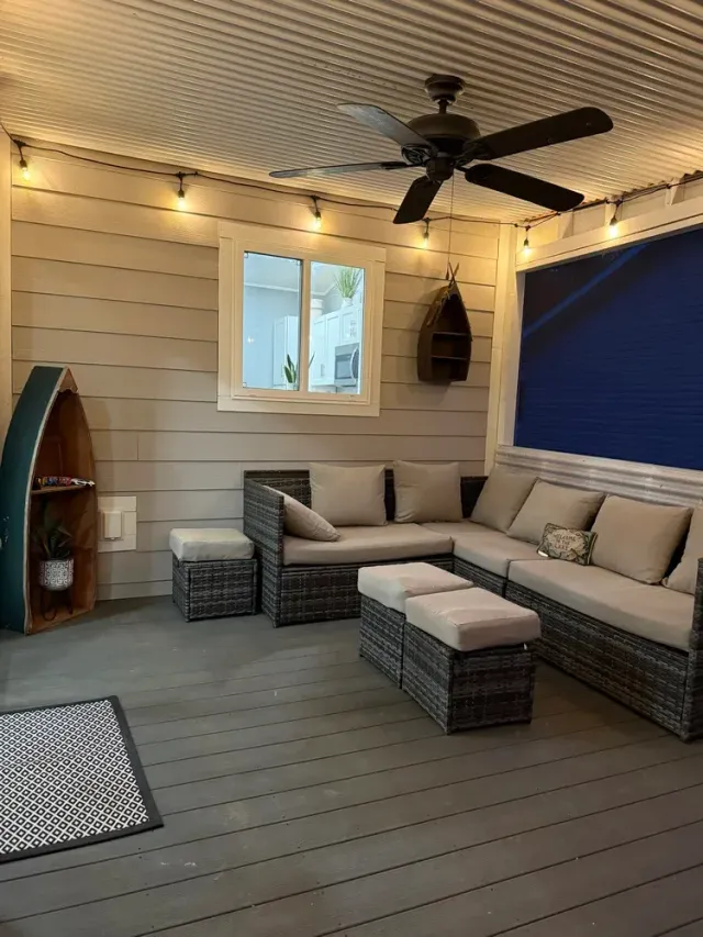Covered patio with wicker sectional, ceiling fan, string lights, and blue privacy shade screen