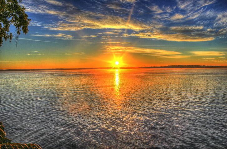 Sunset over a calm lake with golden reflection and dramatic clouds
