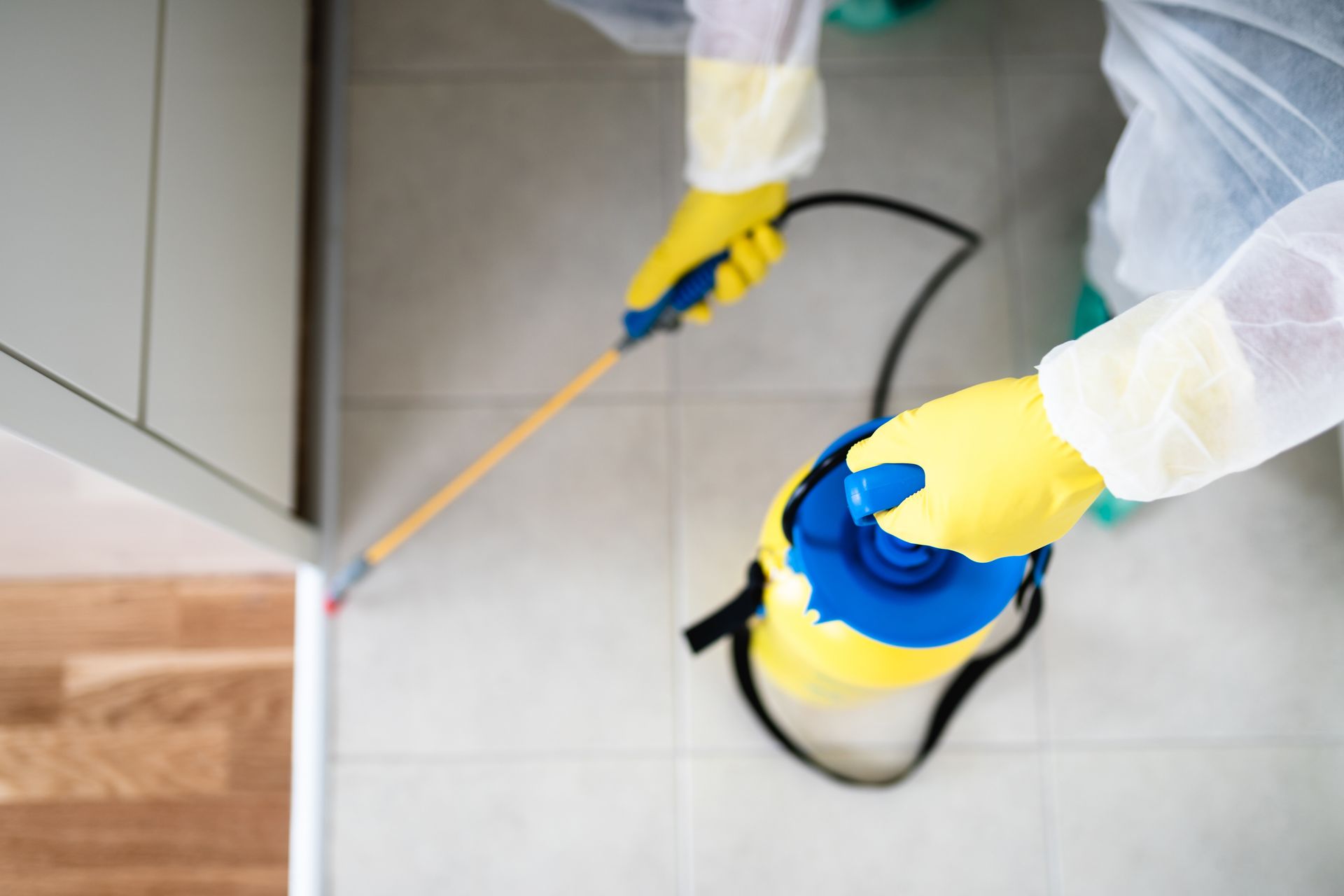 a person in a protective suit is spraying a room with a sprayer .
