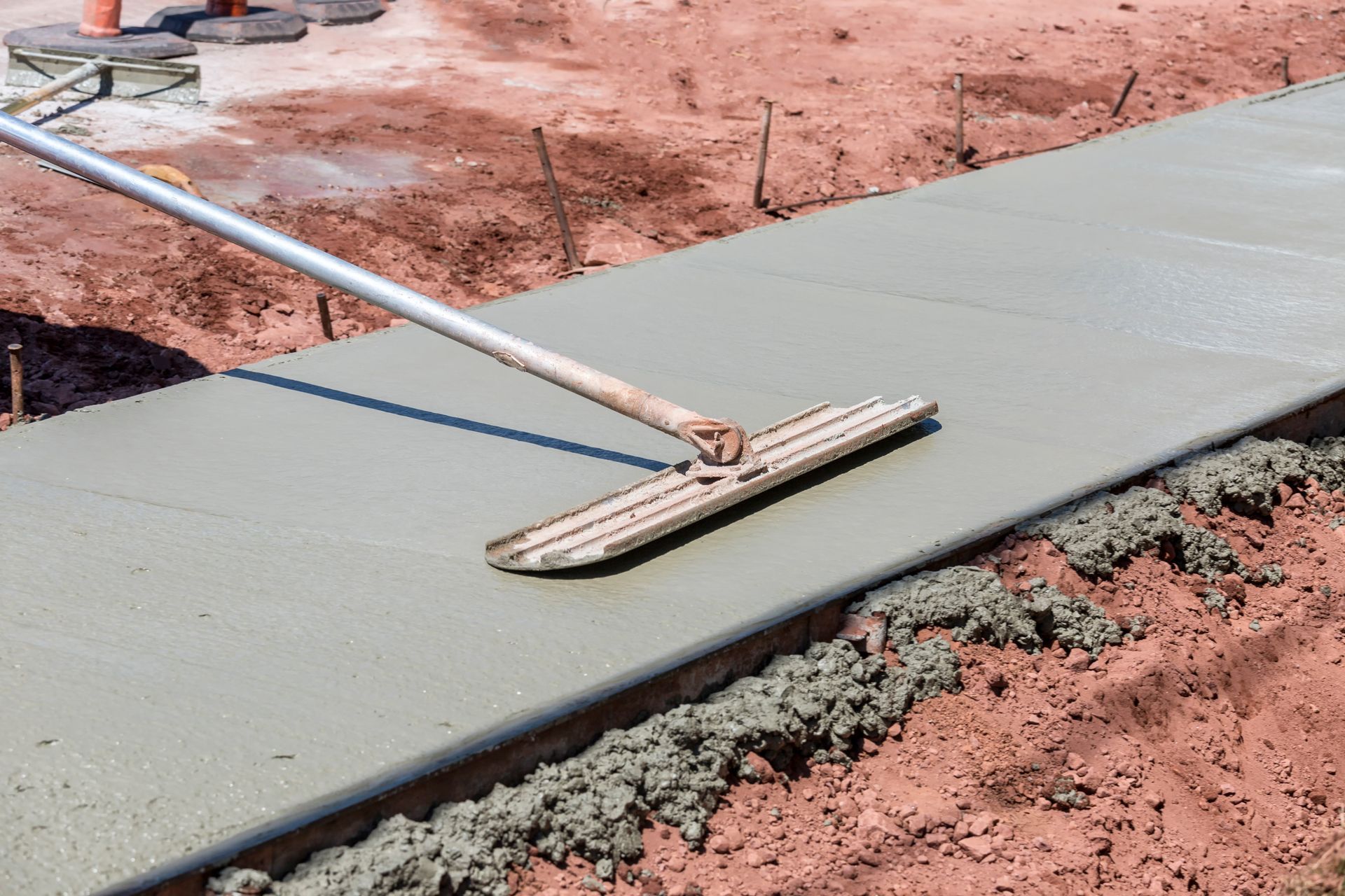 A freshly poured walkway being smoothed with a bull float by professional concrete services.