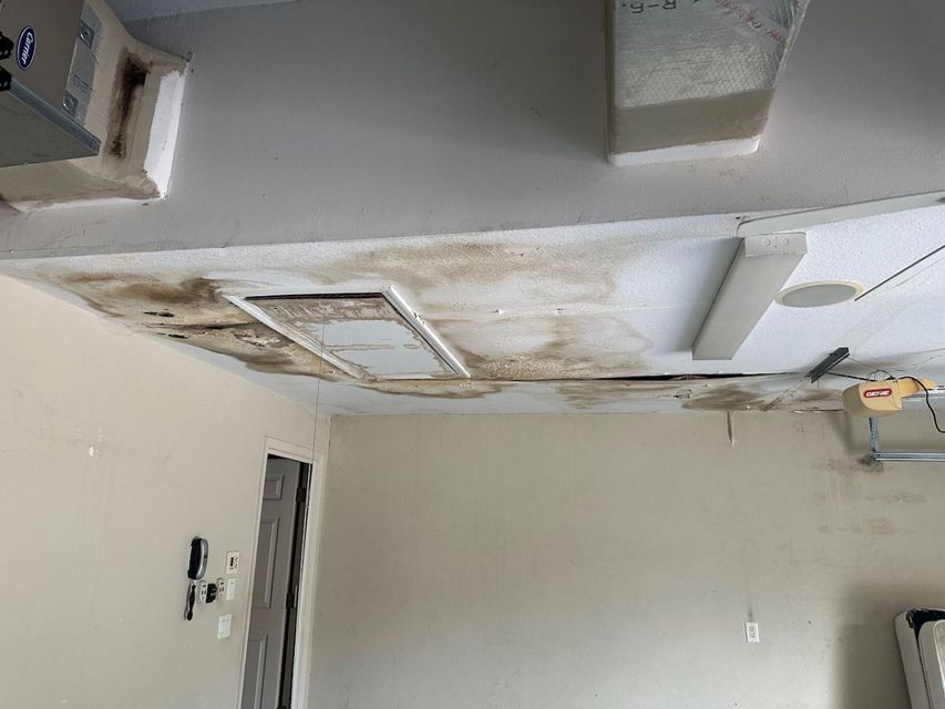 Damaged ceiling with water stains and peeling paint in a mostly empty room